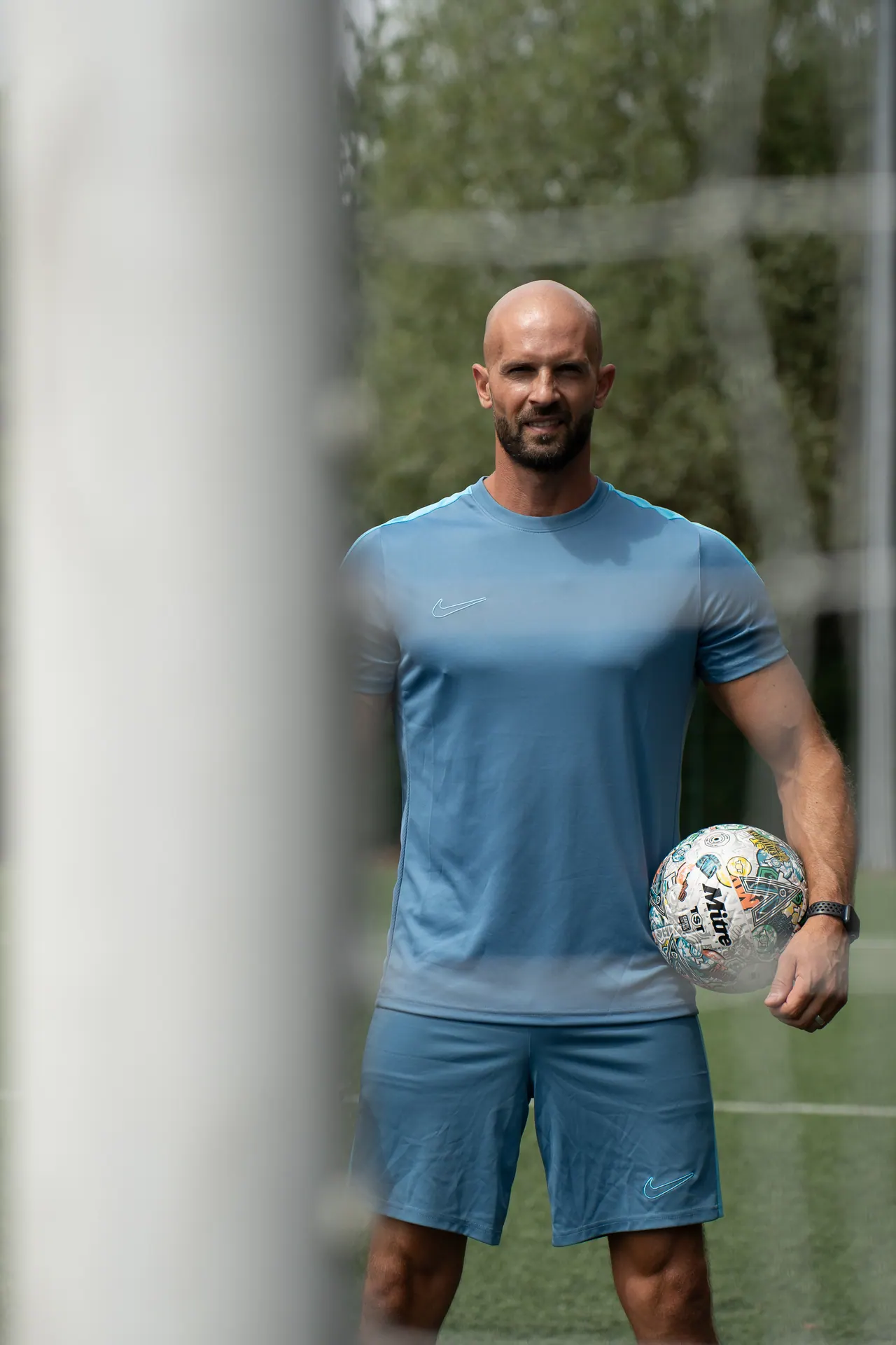 Daniel holding a football on a pitch